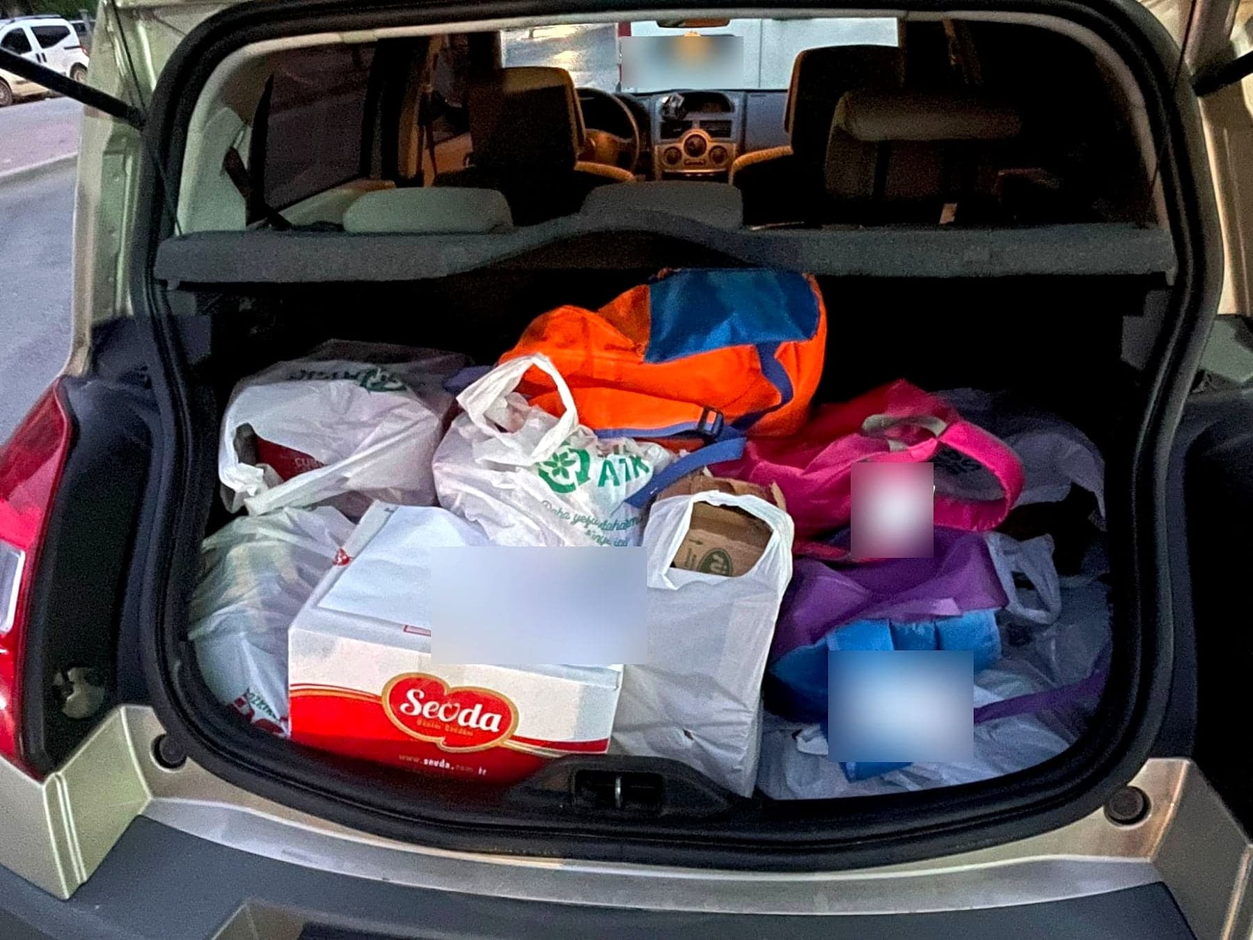 Dağıtıma çıkmadan önce gıda paketleri ve okul çantalarıyla doldurulmuş araç bagajı